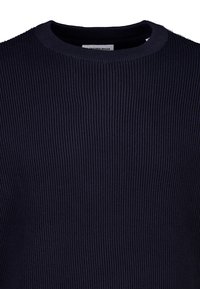 Marineblauer gerippter Pullover mit rundem Halsausschnitt, versehen mit strukturiertem Strick, weichem Stoff und einem im Kragenbereich sichtbaren Etikett.