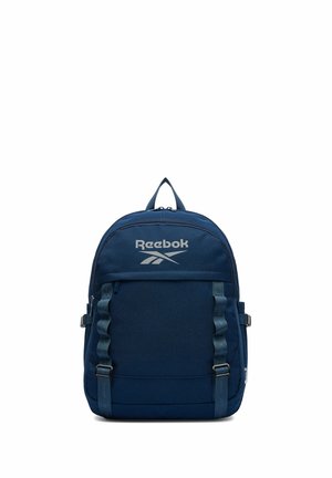 Tmavě modrý batoh Reebok s předním kapsou na zip, nastavitelnými popruhy a horním držadlem na bílém pozadí.