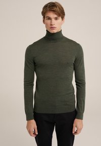 Zeleni pulover s polo ovratnikom, narejen iz fine pletenine, ima dolge rokave in ozek kroj. Na manšetah in robu je rebrasta tekstura.