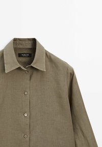 Olivgrön knappad skjorta med krage, med en texturerad tyg och fem matchande knappar framtill för stängning.