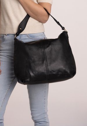 Schwarze Lederhandtasche mit weicher Textur, geschwungenem Design, langem verstellbarem Tragegurt und dezenten Nähdetails auf der Vorderseite.
