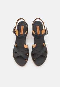 Svarta lädersandaler med strukturerad yta, med korsremmar, spänne och en naturfärgad fotbädd. Platt yttersula.