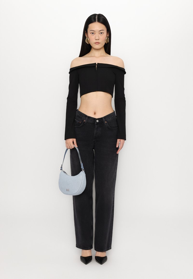 Čierny crop top bez ramienok s dlhými rukávmi, čierne nohavice s vysokým pásom a svetlomodrá kabelka, doplnené o čierne lodičky na vysokom podpätku.