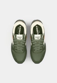 Green athletic sneakers with mesh and suede materials, white accents, flat laces, reinforced toe, and logo on tongue.