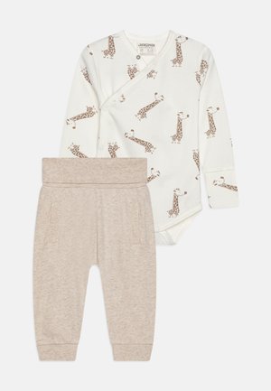 Body bianco per neonato con stampa di giraffe marroni e pantaloni beige con una vita morbida e tasche laterali; materiale in cotone, design semplice.