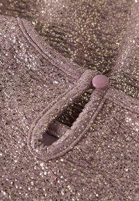 Tela lavanda brillante con una superficie texturizada, presenta un cierre de botón y un brillo sutil de acentos metálicos dispersos.