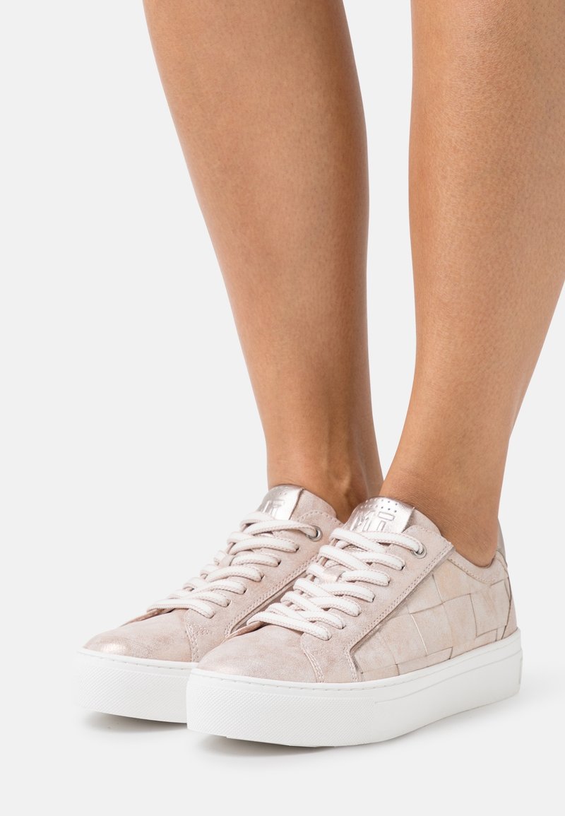 Baskets en daim rose clair avec un motif texturé, semelles en caoutchouc blanches et accents métalliques sur le talon et les œillets. Design à lacets.