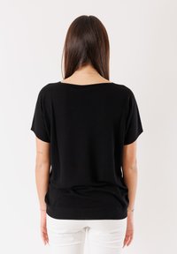 Top nero a maniche corte con vestibilità morbida, caratterizzato da un ampio scollo e orlo a coste. Texture liscia e colore uniforme senza motivi o dettagli.