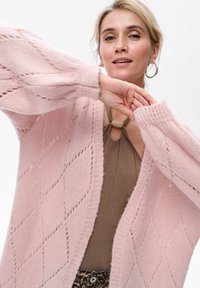 Gebreide cardigan in lichtroze met een ruitpatroon, voorzien van lange, iets opgeblazen mouwen en een open voorkant; zachte textuur.