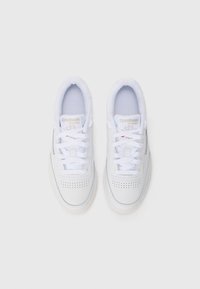 Baskets en cuir blanc avec détails perforés, lacets plats et semelle en caoutchouc texturée. Présente un marquage "Reebok Classic" sur la languette.