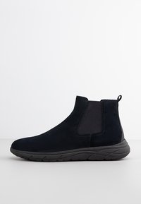 Stivaletto in pelle scamosciata nera con pannelli elastici laterali, linguetta sul retro e suola in gomma resistente, caratterizzato da un design elegante e aerodinamico.