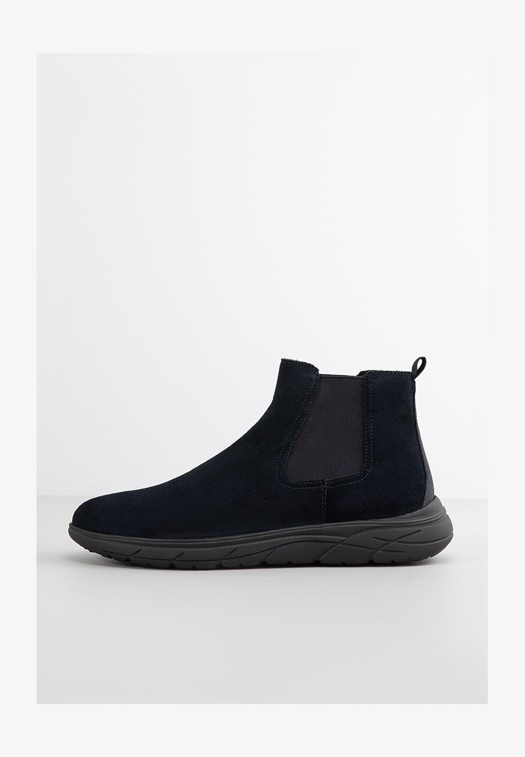 Stivaletto in pelle scamosciata nera con pannelli elastici laterali, linguetta sul retro e suola in gomma resistente, caratterizzato da un design elegante e aerodinamico.