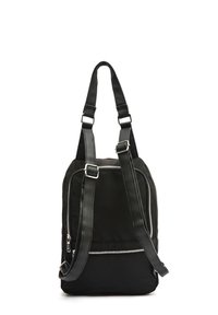 Svart ryggsäck med två justerbara läderremmar, framfickan med dragkedja och silverfärgade detaljer på en vit bakgrund.