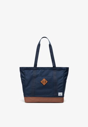 Borsa a tracolla in tela blu navy con accenti in pelle marrone, toppa a forma di diamante al centro e due lunghe cinghie per il trasporto. Texture liscia.