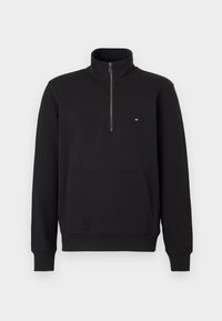 Μαύρο φούτερ με φερμουάρ και ψηλό γιακά, υφή υφάσματος, τσέπη καγκουρό και μικρό λογότυπο στο αριστερό μέρος του στήθους.