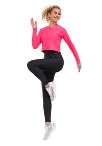 Maglietta fucsia a maniche lunghe, leggings neri a vita alta e scarpe da ginnastica bianche con dettagli multicolore. Il modello è in una posa dinamica.
