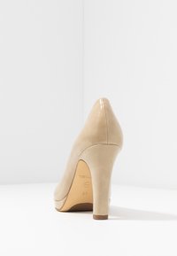 Décolleté beige con punta in vernice lucida, finitura opaca liscia e silhouette affusolata. Presenta una suola testurizzata e un'etichetta di taglia 37.