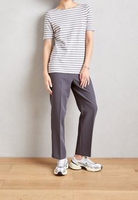 Top de manga corta a rayas grises y blancas, pantalones grises y zapatillas deportivas plateadas. El top tiene un escote barco y un corte relajado.
