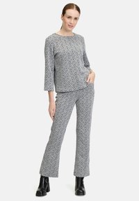 Outfit a righe grigie e bianche composto da una maglietta a maniche lunghe e pantaloni dritti, realizzato in un tessuto texture con design geometrici.