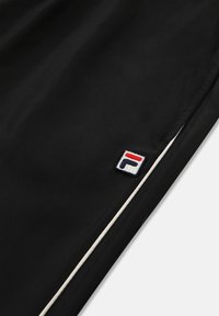 Zwarte sportbroek met een witte bies en een rechthoekig logo in rood, blauw en wit aan de linkerkant. Gladde textuur.