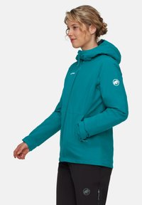 Giacca impermeabile color turchese con cappuccio, zip frontale e due tasche laterali. Presenta un logo sulla manica e una texture liscia.