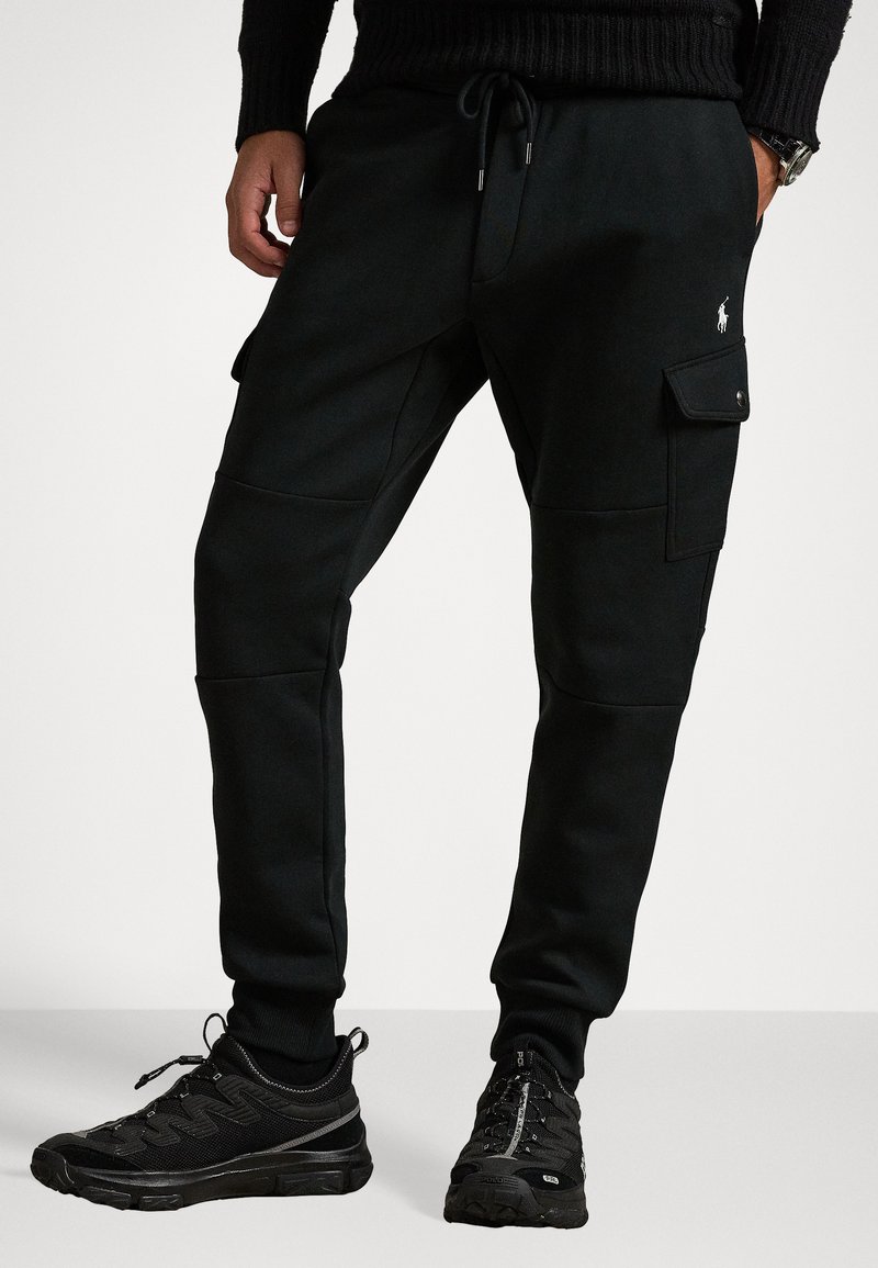 Svarta joggers i en bomullsblandning, med cargofickor, dragsko i midjan och ribbade ärmar. Matchas med svarta texturerade sneakers.