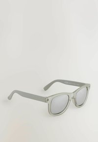 Lunettes de soleil surdimensionnées et claires avec des montures en plastique translucide gris clair et des verres gris. Présente des branches droites et des accents minimaux.