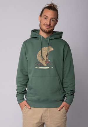 Green hoodie made of cotton blend, featuring a bear graphic on a bike. It has a kangaroo pocket and drawstrings on the hood.