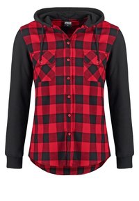 Camicia di flanella a quadri rossi e neri con cappuccio; presenta maniche lunghe nere, due tasche frontali e un orlo curvato. Realizzata in tessuto morbido.