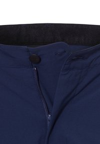 Marineblauwe stoffen broek heeft een ritssluiting, knoopsluiting en een elastische tailleband. Gladde textuur met minimale stikdetails.
