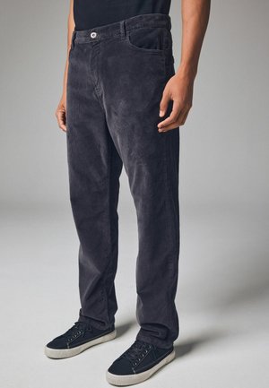 Dunkelgraue Cordhosen mit geradem Bein, ausgestattet mit Fronttaschen, einem Knopfverschluss und dezent gerippter Textur. Tragen mit schwarzen Sneakers.