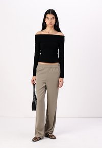 Juodas off-the-shoulder ilgomis rankovėmis marškinėliai, smėlio spalvos plačios kojos kelnės, gyvūnų rašto šlepetės ir mažas juodas rankinukas. Lygūs audiniai ir prigludusi forma.