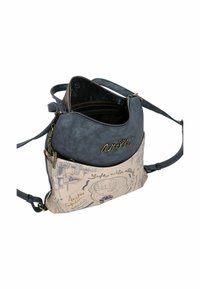 Zweifarbige Handtasche mit einem dunkelblauen oberen Abschnitt aus strukturiertem Material und einem beigen unteren Abschnitt mit bedruckten Illustrationen und Schriftzügen.