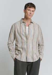 Gestreepte button-up blouse in beige, blauwe en bruine tinten. Lichtgewicht stof met een zachte textuur en een ontspannen pasvorm. Lange mouwen en afgeronde zoom.