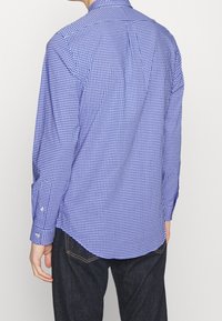 Niebieska i biała koszula w kratę z długim rękawem, o prostym kroju, z mankietami na guziki i klasycznym kołnierzykiem, zestawiona z ciemnymi dżinsami.