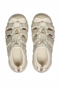 Scarpe da esterno beige chiaro con tomaia in mesh testurizzato, fasce elastiche e suola imbottita con un motivo stampato.