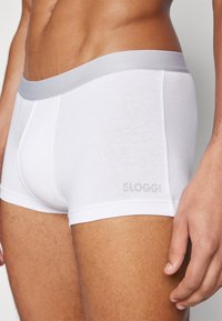 Fehér pamut boxer alsónadrág, puha szürke elasztikus derékpánttal. Simaságot biztosító anyag és a "SLOGGI" logó nyomata az oldalon.