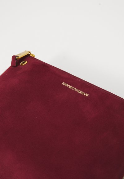 Burgundia sueded kott kuldse tõmbluku ja valgele taustale lõpetatud kuldse Emporio Armani logoga.