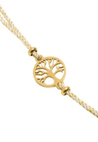 Złota zawieszka w kształcie drzewa życia na splecionym białym i złotym sznurku. Zawieszka posiada misternie wycinane detale w formie okrągłego wzoru.