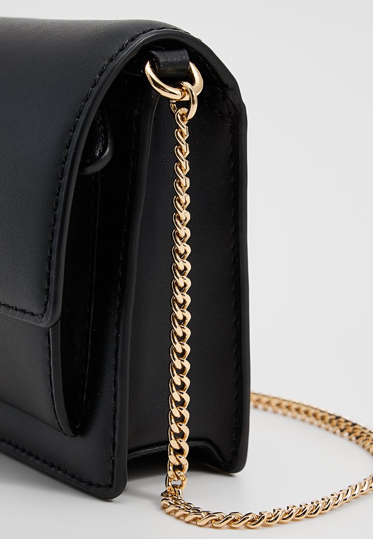Czarna skórzana torebka z złotym łańcuszkiem, z klapką na zamek i gładką teksturą. Kompaktowy design idealny na wieczorne wyjścia.