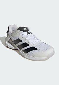 Białe sportowe buty z czarnymi akcentami i trzema czarnymi paskami. Posiadają siateczkowy wierzch, wyściełany kołnierz oraz gumową podeszwę o teksturowanym wykończeniu.