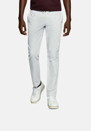 Witte katoenen broek met strepen, een trekkoord in de taille, taps toelopende pasvorm en zijzakken, gecombineerd met witte sneakers.