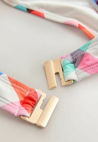 Sangles colorées à motifs en tissu rose, rouge et bleu avec des fermoirs en métal doré. Texture matelassée douce, conçue pour le confort et le soutien.