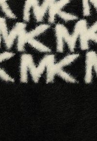 Tapis en peluche noir et blanc, arborant un motif de logo répété avec une texture douce et duveteuse, mettant en contraste des lettres audacieuses sur un fond sombre.