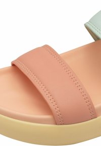 Pink slide sandal with a wide strap, smooth texture, and contrasting cream midsole; features clean stitching and a pastel green accent.