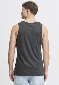 Ärmelloses graues Tanktop aus weichem Stoff, mit rundem Ausschnitt und lockerer Passform. Die Rückansicht zeigt eine glatte Textur und ein minimalistisches Design.