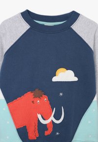 Blue and gray children's sweater with red woolly mammoth applique, white tusks, yellow sun partially covered by a white cloud, and small white embroidered stars.