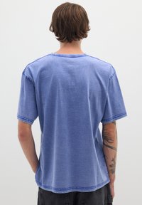 Blauwe T-shirt met korte mouwen en een relaxte pasvorm, gemaakt van zachte katoen. Heeft contrasterende stiksels, een ronde hals en onafgewerkte randen.