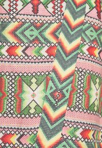 Tessuto colorato con un motivo geometrico in verde, rosso, giallo e rosa, con forme a zigzag e diamante, tessuto testurizzato.