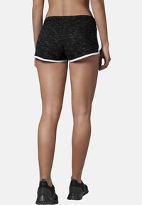 Černé sportovní šortky s melírovanou texturou, s bílým lemem na spodním okraji a elastickým pasem pro pohodlí.
